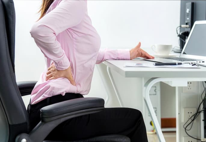 lady with back pain sitting on a desk